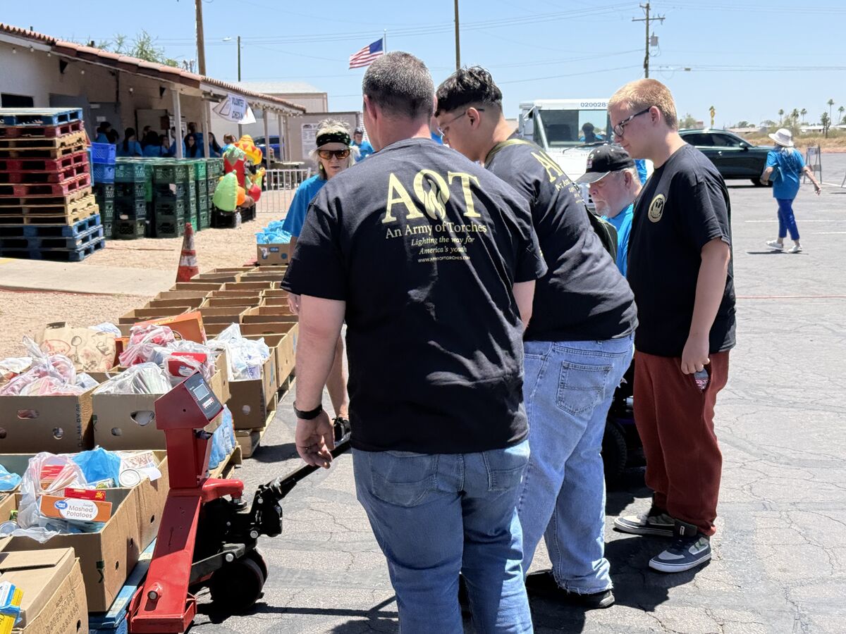 AOT volunteers using a pallet jack to move heavy boxes of donated food at the food bank