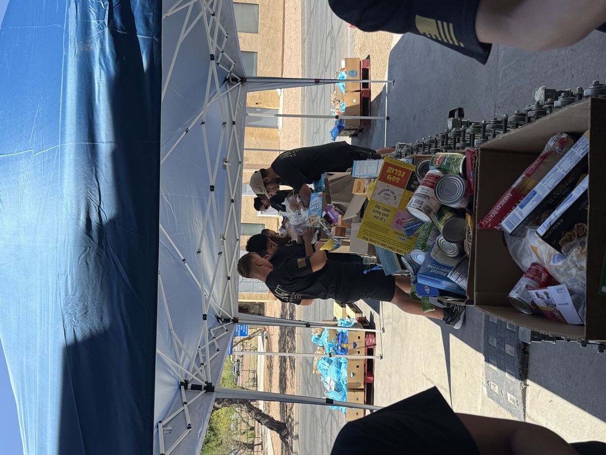 AOT volunteers sorting non-perishable food items under a blue canopy tent