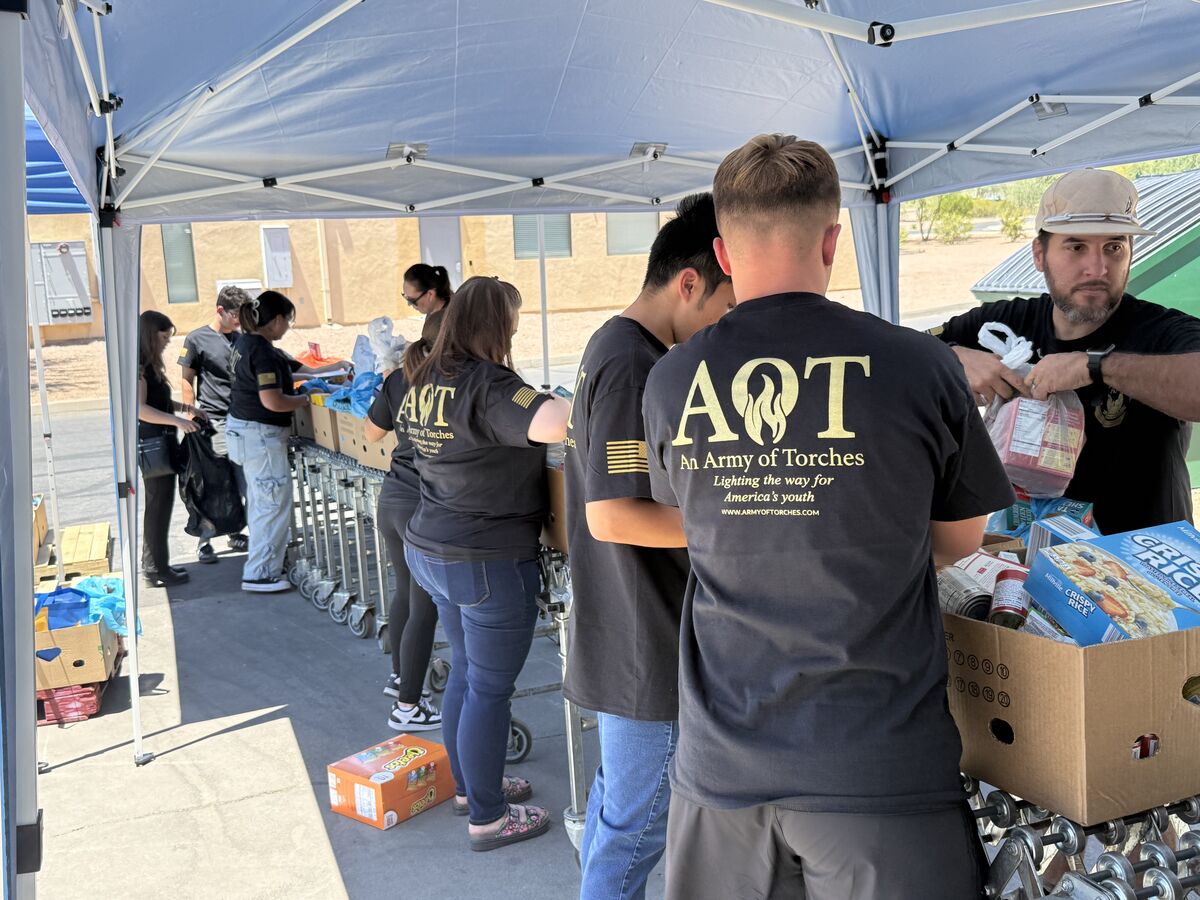AOT team members packing food items together under the tent with AOT shirts visible
