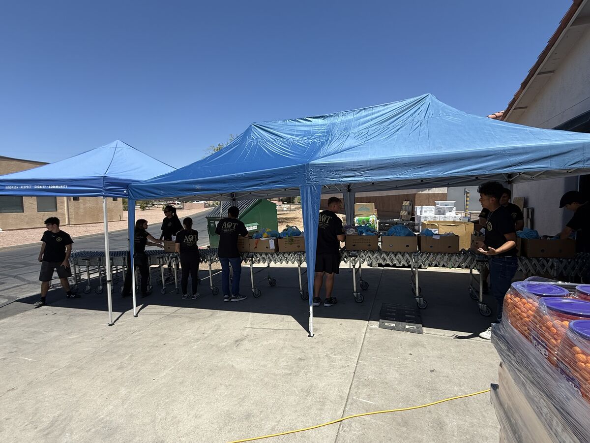 AOT volunteers working under blue canopy tents sorting food donations into boxes